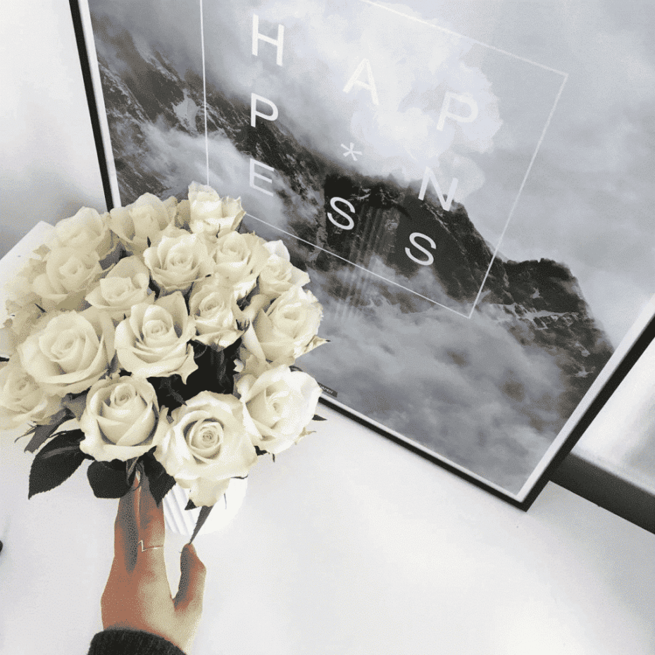 Lys plakat i sort billederamme med lyngbyvase og lyse blomster
