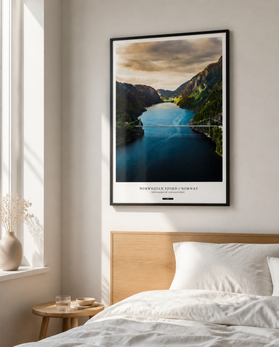 NORWEGIAN FJORD plakat i sort ramme over en lys egetræsseng i et nordisk soveværelse med dagslys.