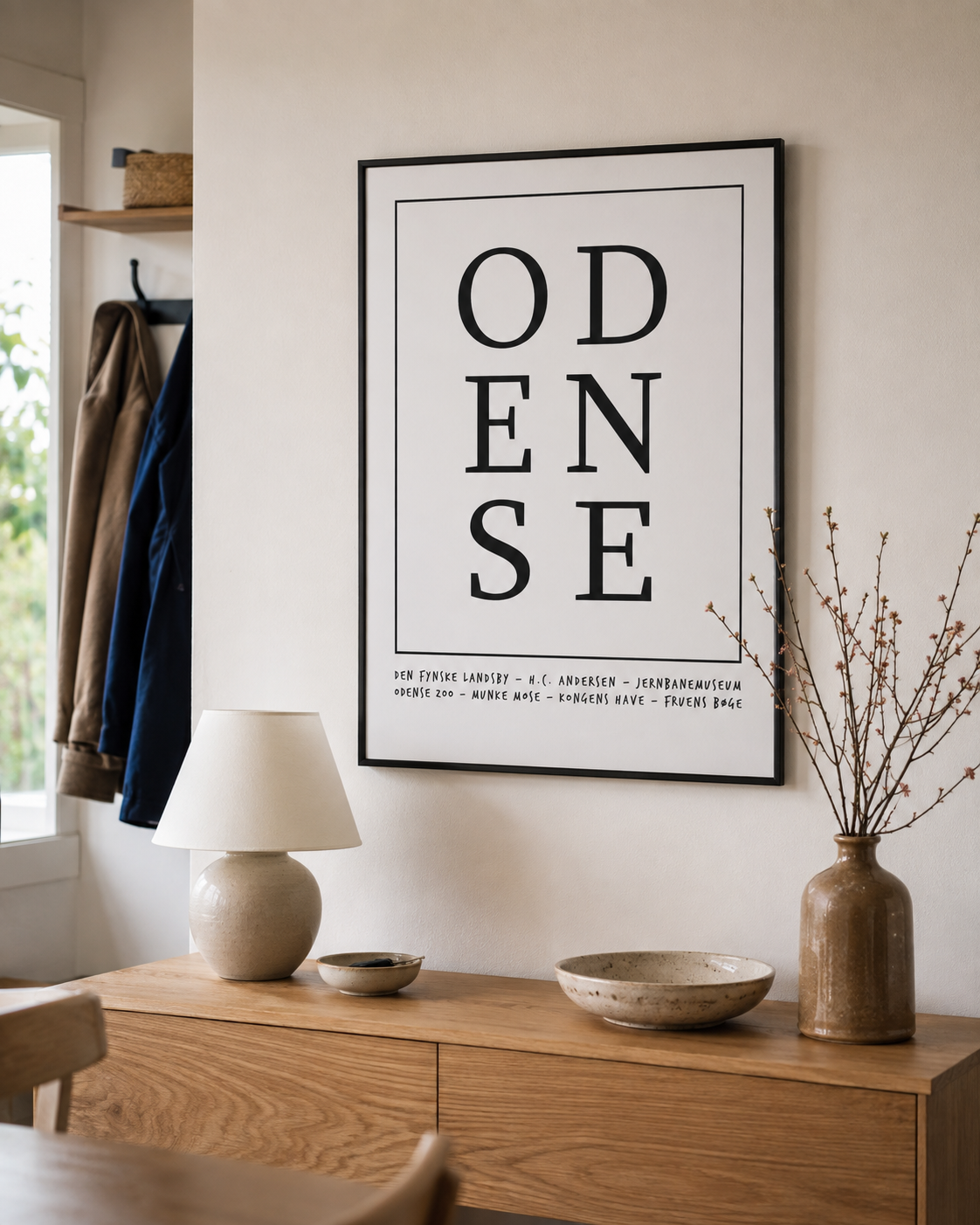 ODENSE KASPERBENJAMIN miljøbillede Odense plakat i sort ramme i en lys dansk entré med naturligt dagslys