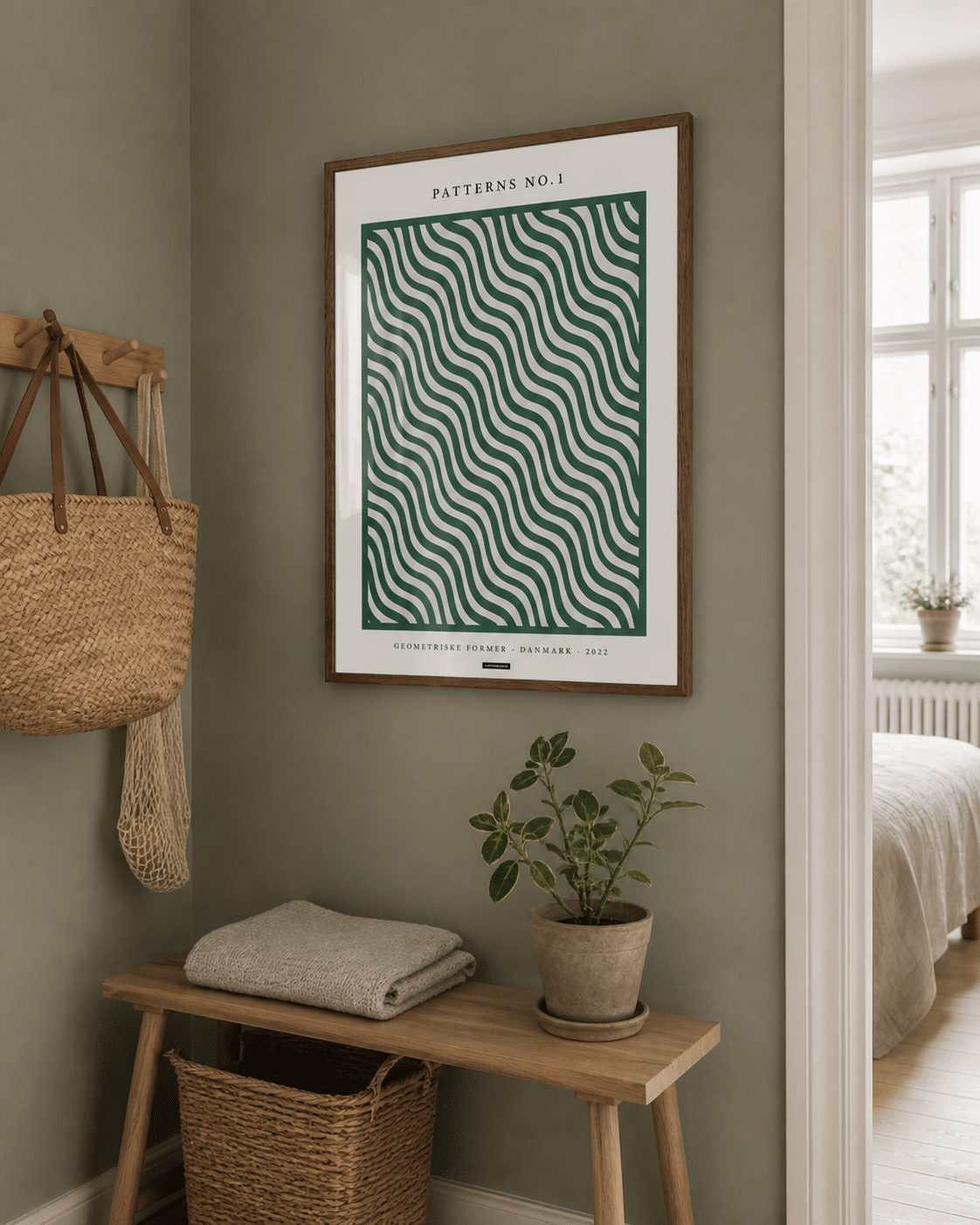 Patterns No.1 miljøbillede hero hallway KASPERBENJAMIN Patterns No.1-plakaten med grønne bølger i en varm træramme hænger på en grøn væg i en naturlig dansk entré med bænk, kurv og dagslys.